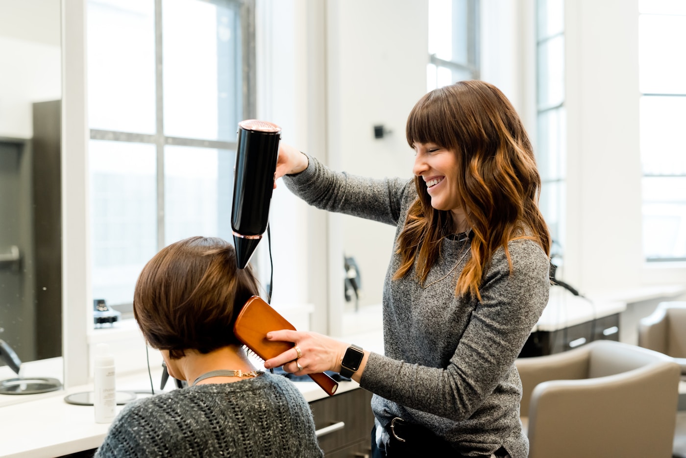 Hairstylist shaping wet hair at a salon station